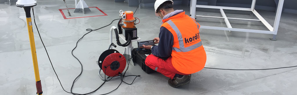 Kordil surveyor operating positioning equipment beside a GNSS antenna