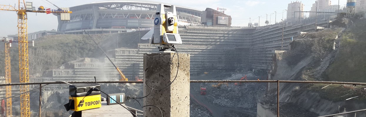 Total station on a survey pillar overlooking a construction excavation