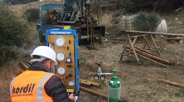 Kordil technician operating a pressuremeter control unit beside a borehole drilling rig